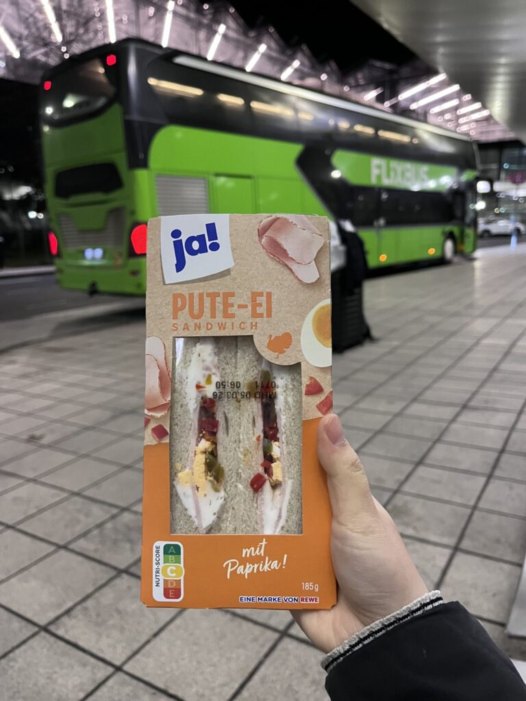 バスの前でサンドイッチを掲げる様子